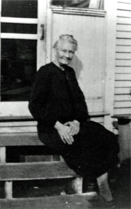 Margaret Ann (Bruegger) Kienlen, ca. 1938, is seated on back steps of a house.